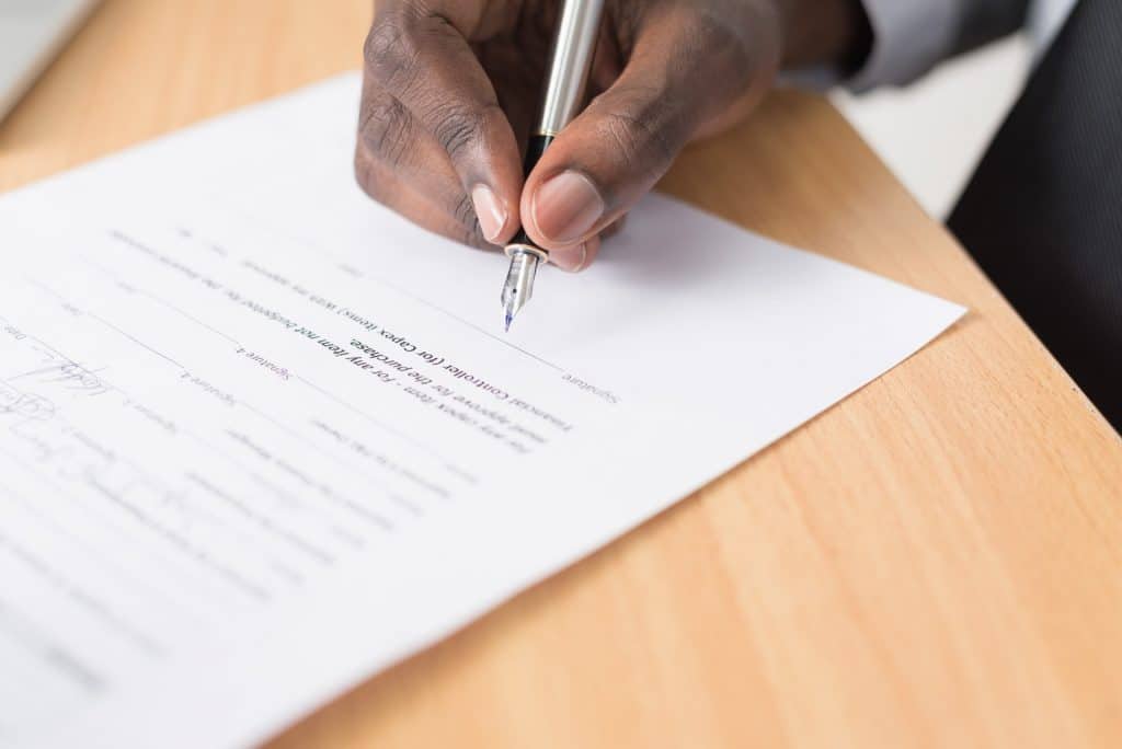 Man signing a contract agreeing to an indemnity clause