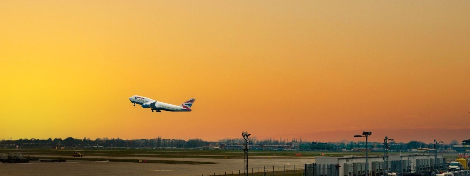 A plane is taking off from an airport during sunset.